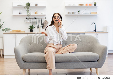 Woman relaxing on sofa and using modern smartphone for talking with family. Woman relaxing on sofa and using modern smartphone for talking with family. 111013568