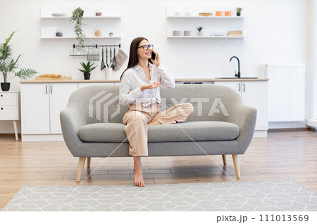 Woman relaxing on sofa and using modern smartphone for talking with family. Woman relaxing on sofa and using modern smartphone for talking with family. 111013569