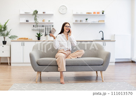 Woman relaxing on sofa and using modern smartphone for talking with family. Woman relaxing on sofa and using modern smartphone for talking with family. 111013570