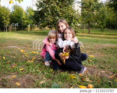 Joyful children three little girls playing in the autumn park together 111013787