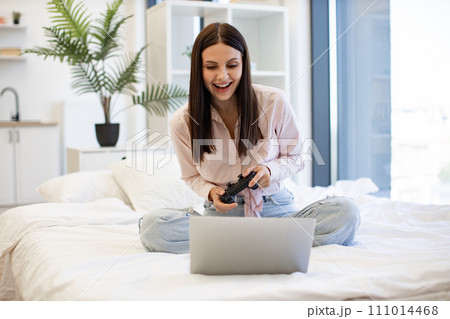 Caucasian brunette using modern devices enjoying favorite video game on weekend. Caucasian brunette using modern devices enjoying favorite video game on weekend. 111014468