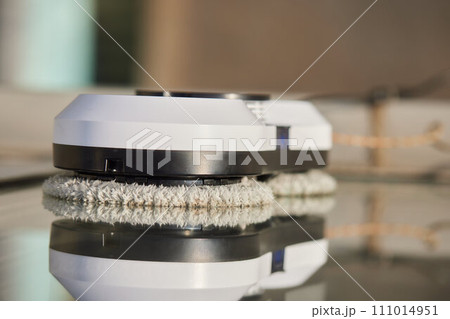 A window cleaner robot washes glass against the backdrop of multi-storey buildings. 111014951