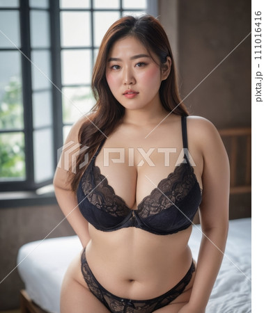 an asian woman in black lingerie posing on a bed 111016416