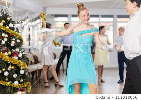 Teenagers in holiday clothes dancing swing dance near Christmas tree 111018056