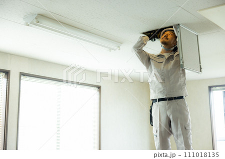 天井を点検する作業着の男性  天井を点検する作業着の男性  111018135