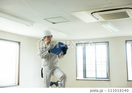 天井を点検する作業着の男性  天井を点検する作業着の男性  111018140