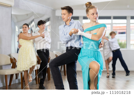 Enthusiastic adolescent girl and boy dancing in pair in dance studio 111018218