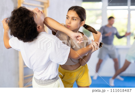 Boy and girl train to perform works out blow to jaw at opponent, while learning self-defense 111018487