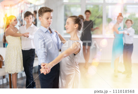 Positive teen boy and girl are dancing classic version of waltz in couple during lesson at studio Positive teen boy and girl are dancing classic version of waltz in couple during lesson at studio 111018568
