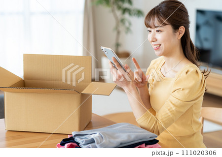 リビングで段ボールに荷造りする女性 リビングで段ボールに荷造りする女性 111020306