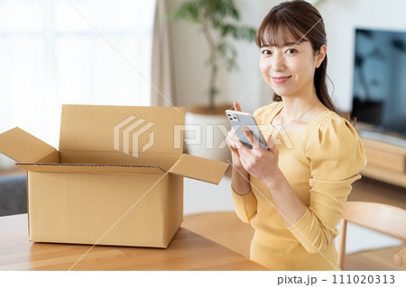 リビングで段ボールに荷造りする女性 111020313
