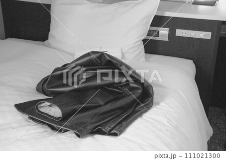 ベッドに脱ぎ捨てられた革のコート ベッドに脱ぎ捨てられた革のコート 111021300