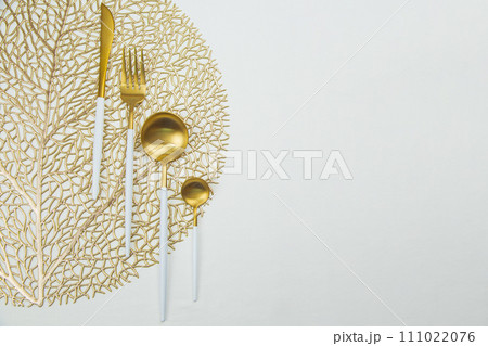 The food utensils, gold with a white handle, lie on a gold napkin on a white background. The concept of eating, the concept of serving. High quality photo 111022076