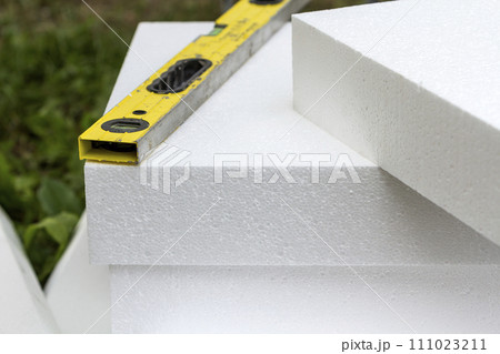Close-up detail of stack of white rigid polyurethane foam sheets for house insulation and level. Modern technology, renovation, professional job, energy saving, alternative for mineral wool concept. 111023211