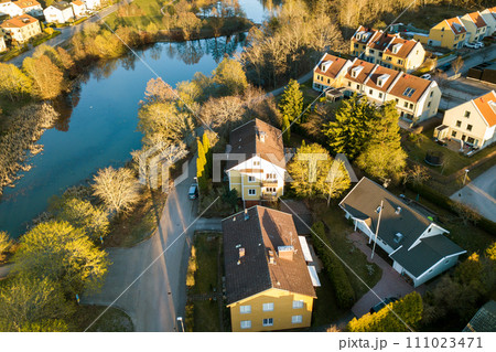 Aerial view of residential houses with red roofs and streets with parked cars in rural town area. Quiet suburbs of a modern european city. Aerial view of residential houses with red roofs and streets with parked cars in rural town area. Quiet suburbs of a modern european city. 111023471