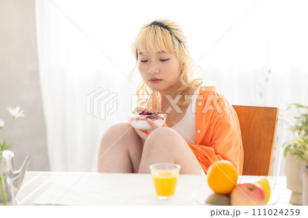 ヨーグルトを食べる若い金髪女性 111024259