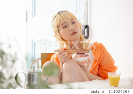 ヨーグルトを食べる若い金髪女性 111024268