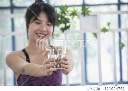 Woman drinking water hands holding cold mineral water cool drinking. Asian women smile laugh look away health care home fitness lifestyle. Cheerful Beautiful female drink glass of water smile face 111024761