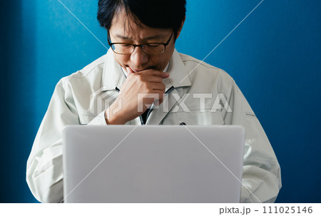 パソコンを見て悩む作業服の男性 パソコンを見て悩む作業服の男性 111025146
