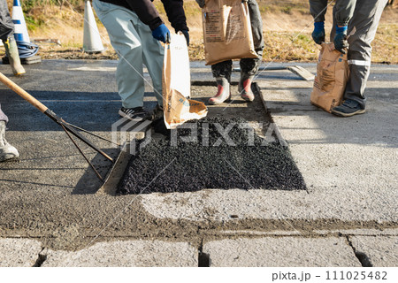 道路工事　アスファルトの舗装復旧工事　常温合材の敷均し 111025482