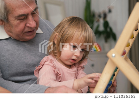 Grandfather playing toys with grandson and young granddaughter indoor. Old man grandpa studying with his grandchildren at weekend. Senior male having fun with kids. Happy multigeneration family video Grandfather playing toys with grandson and young granddaughter indoor. Old man grandpa studying with his grandchildren at weekend. Senior male having fun with kids. Happy multigeneration family video 111026365