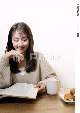 リビングで本を読みながらくつろぐ女性 111026804