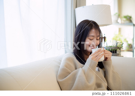 ソファーでくつろぎながらコーヒーを飲む女性 111026861