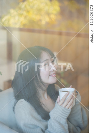 ソファーでくつろぎながらコーヒーを飲む女性 111026872