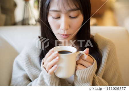 ソファーでくつろぎながらコーヒーを飲む女性 ソファーでくつろぎながらコーヒーを飲む女性 111026877