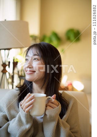 ソファーでくつろぎながらコーヒーを飲む女性 111026882