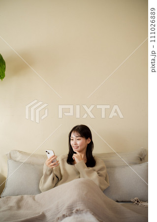 部屋のベッドでスマホを見る女性 部屋のベッドでスマホを見る女性 111026889