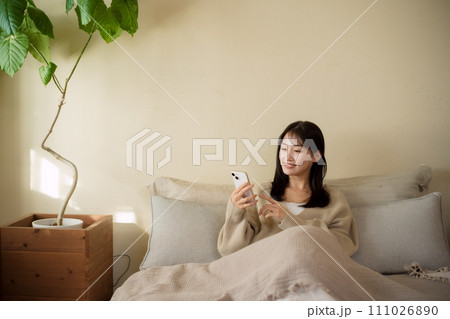 部屋のベッドでスマホを見る女性 部屋のベッドでスマホを見る女性 111026890