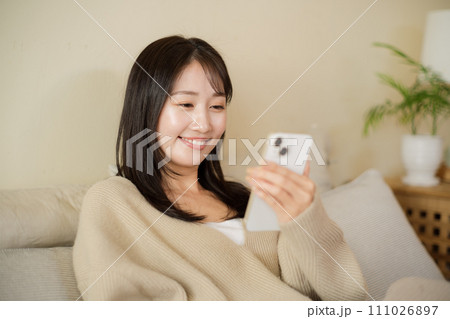 部屋のベッドでスマホを見る女性 111026897