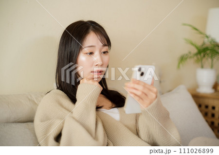 部屋のベッドでスマホを見る女性 部屋のベッドでスマホを見る女性 111026899
