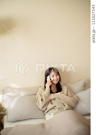 ベッドの上でスマートフォンを触る女性 111027143