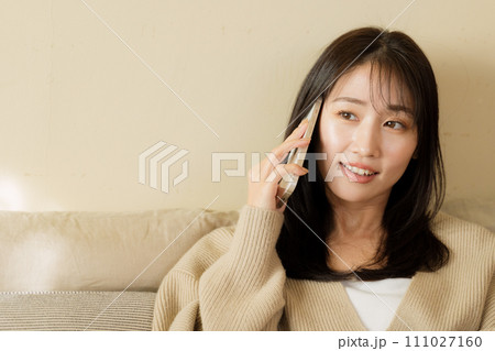 ベッドの上でスマートフォンを触る女性 111027160