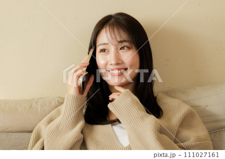 ベッドの上でスマートフォンを触る女性 111027161