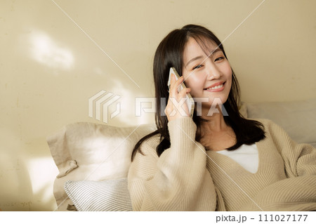 ベッドの上でスマートフォンを触る女性 ベッドの上でスマートフォンを触る女性 111027177
