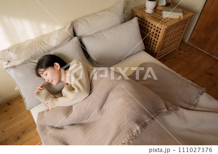 寝室のベッドで眠る女性 111027376