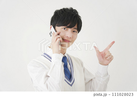 スマートフォンで電話しながらチャックサインをする男子高校生 白背景 スマートフォンで電話しながらチャックサインをする男子高校生 白背景 111028023