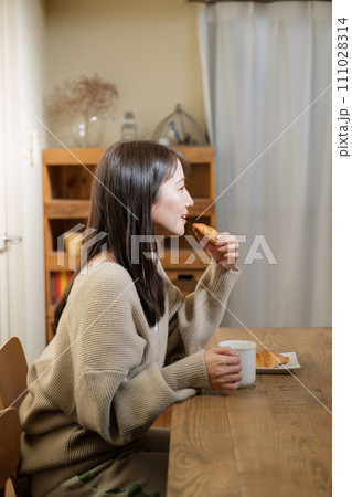 リビングのテーブルで食事を楽しむ女性 リビングのテーブルで食事を楽しむ女性 111028314