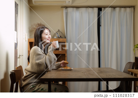 リビングのテーブルで食事を楽しむ女性 111028317