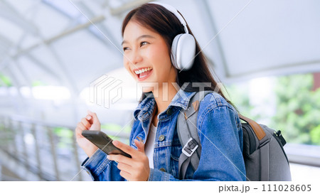 Portrait of happy young asian woman listening music online with wireless headphones 111028605