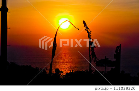 views of Penjor, Janur and Balinese temples with the sunset of Uluwatu, Bali 111029220