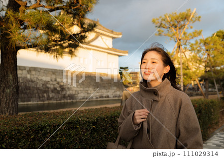 夕陽が沈む街中を散歩する女性 111029314