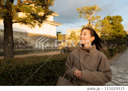 夕陽が沈む街中を散歩する女性 111029315