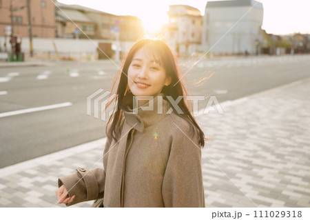 夕陽が沈む街中を散歩する女性 夕陽が沈む街中を散歩する女性 111029318