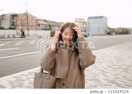 夕陽が沈む街中を散歩する女性 夕陽が沈む街中を散歩する女性 111029324