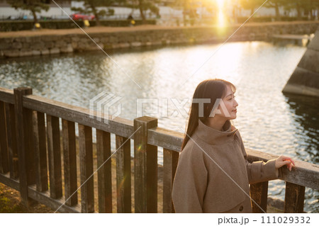 夕陽が沈む街中を散歩する女性 夕陽が沈む街中を散歩する女性 111029332
