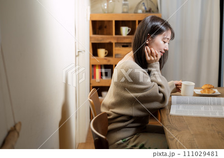 リビングのテーブルで読書する女性 111029481